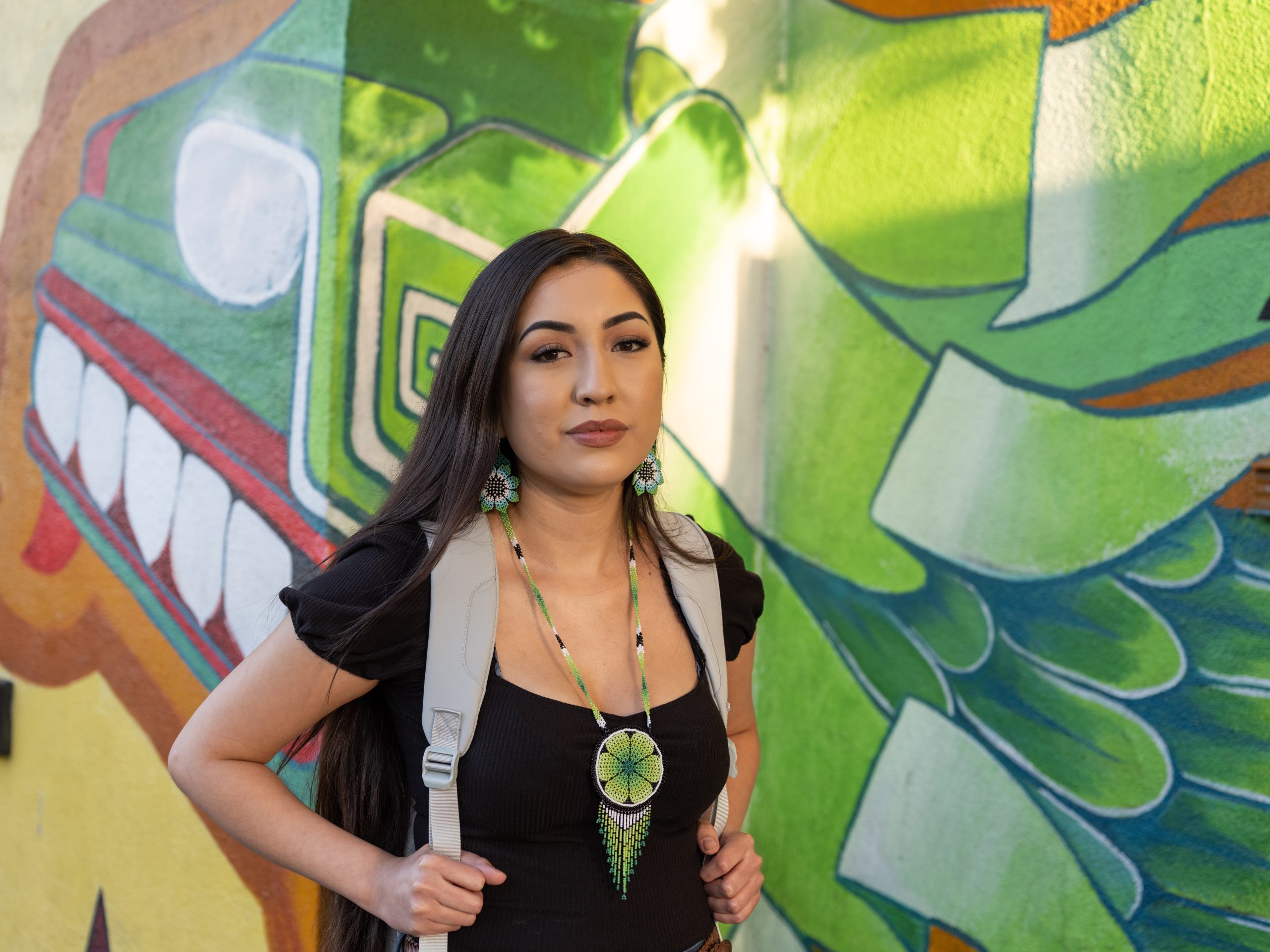 Research collaboration for Ontario entrepreneurs Portrait of an Indigenous business owner standing in front of a vibrant mural, representing community pride and participation in OCIP’s innovation programs.